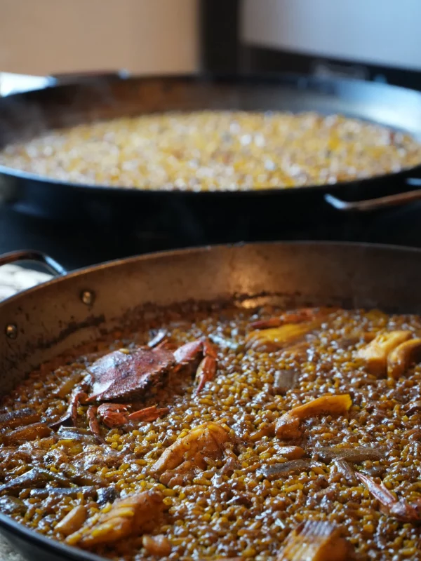 Dos paellas de arroz cocinándose al fuego en La Giralda, Dénia