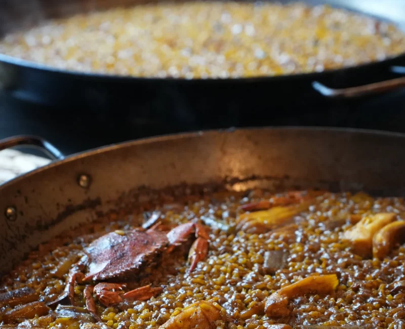 Dos paellas de arroz cocinándose al fuego en La Giralda, Dénia