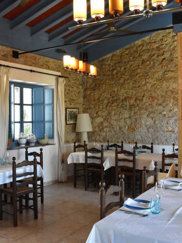 Salón interior con paredes de piedra y techo de madera de La Giralda, Dénia